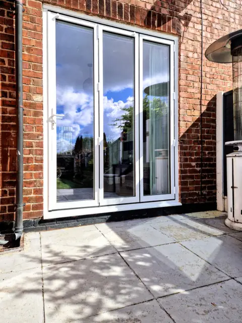 The same white bifold doors closed, seen from the patio