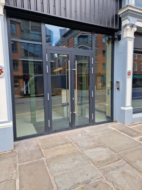 Aluminium commercial entrance screen with double doors onto a city pavement
