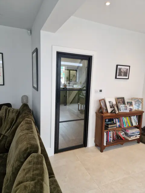 Steel-look internal door between a living room and kitchen, clear glazing with a low bar