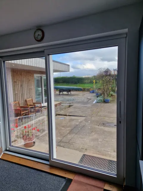 Aluminium slider from a living room onto a patio, open field beyond